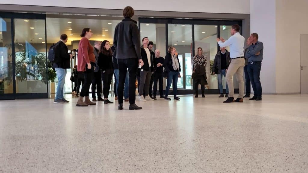 Groep mensen in een gebouw, een iemand is aan het woord.