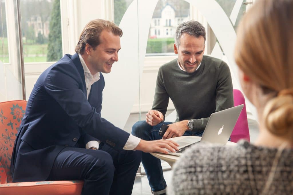 mensen in gesprek rondom Macbook laptop